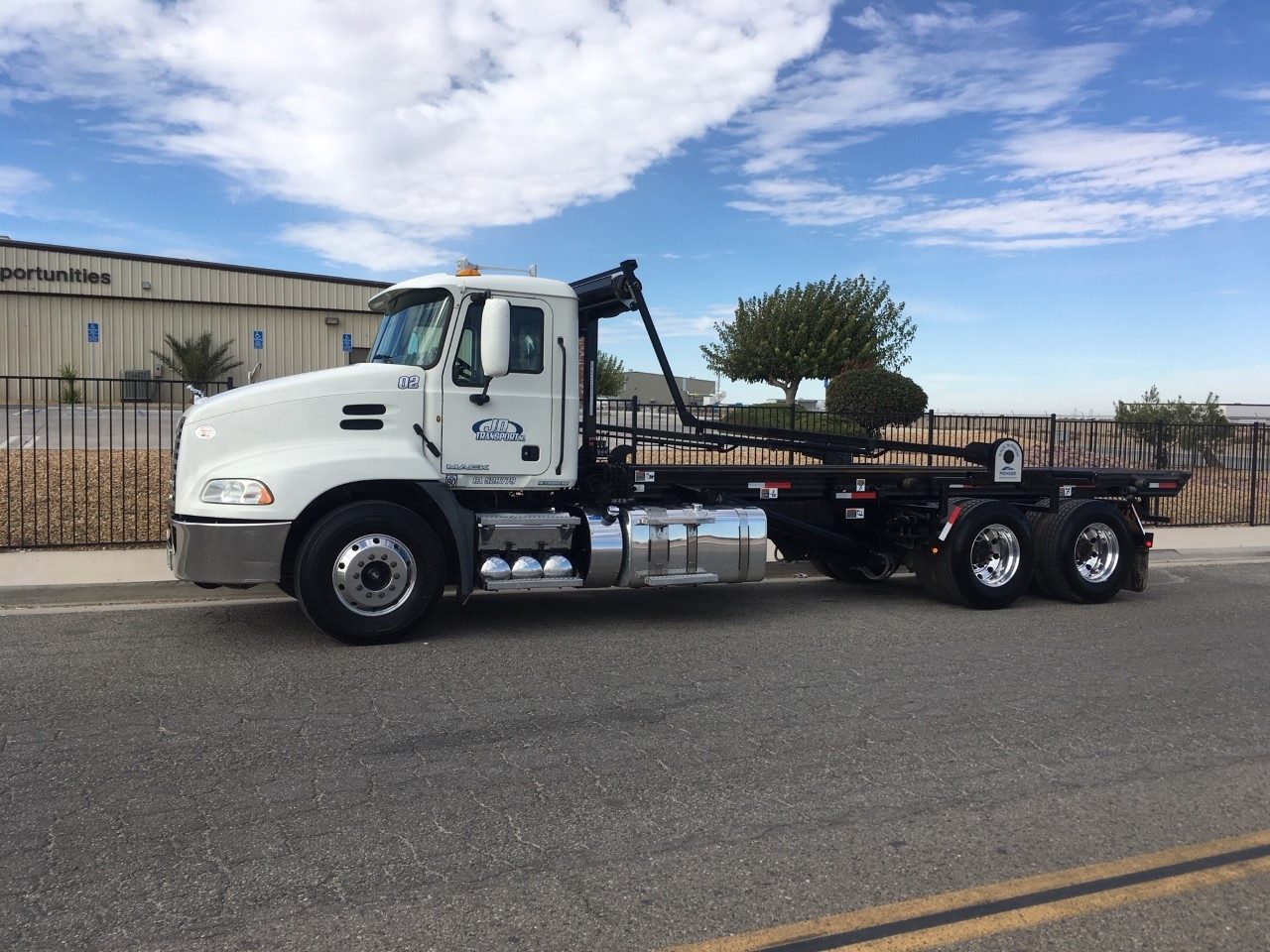 Side profile of a JD Transport roll-off truck with the flatbed extended
