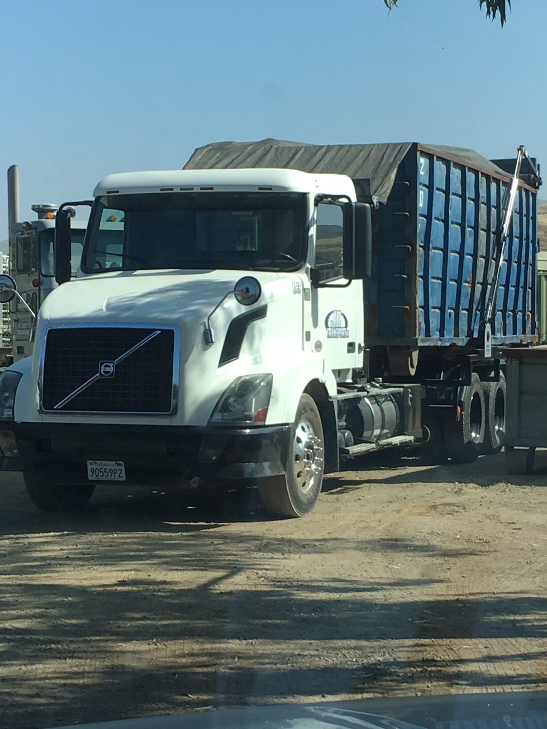 White Volvo JD Transport roll-off truck hauling a loaded 20 yard scrap metal container
